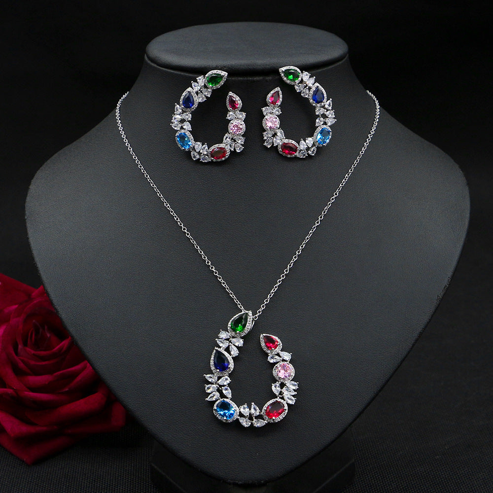 Jewelry set with necklace and earrings on a black stand with a red rose.
